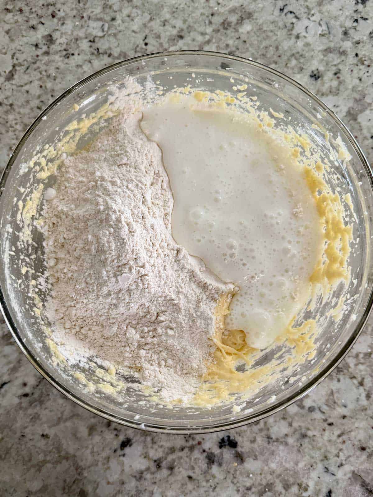 Buttermilk and the dry ingredients being added to the butter egg mixture in a bowl.