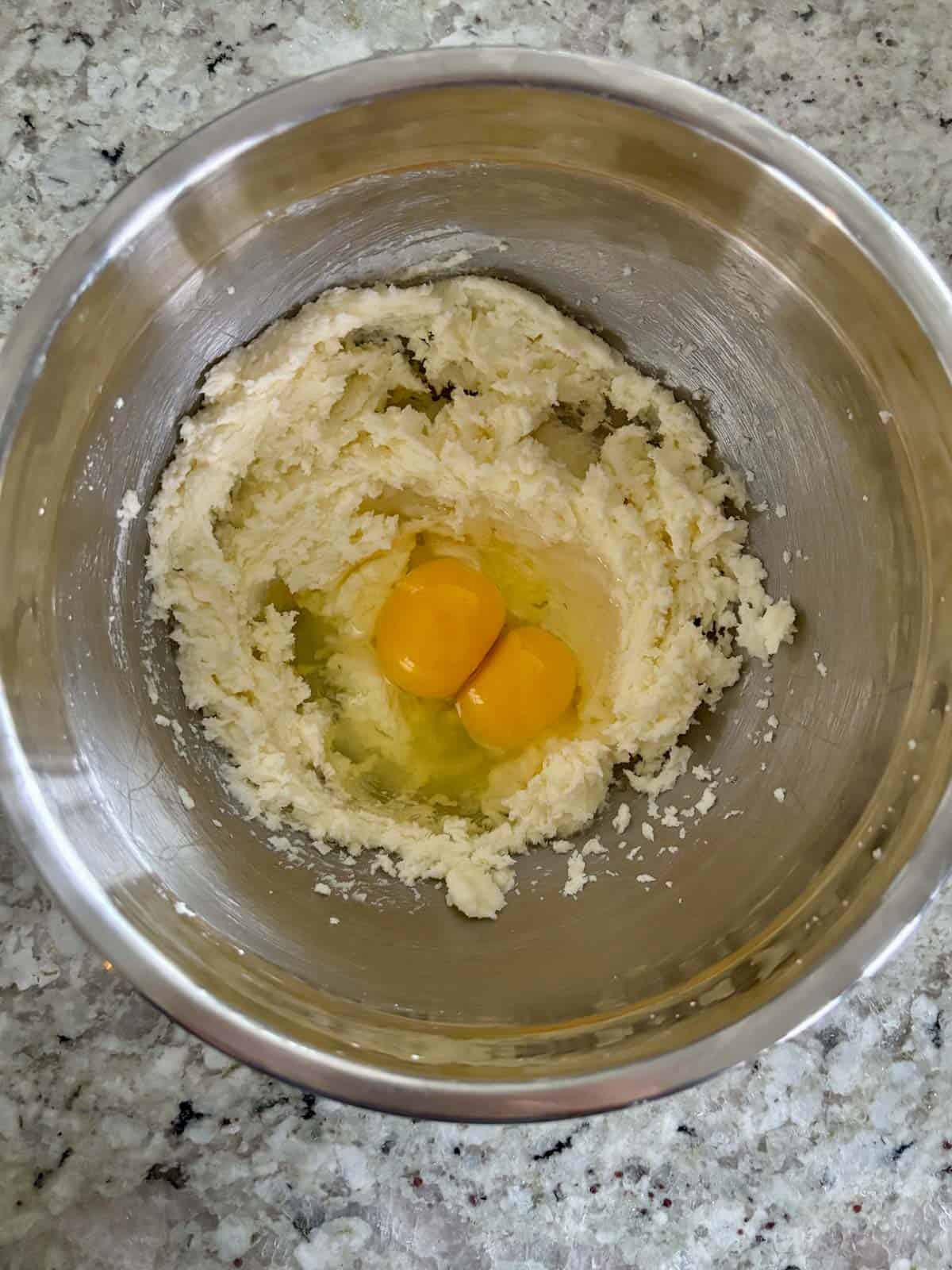 Eggs being added to the creamed butter and sugar in a bowl.
