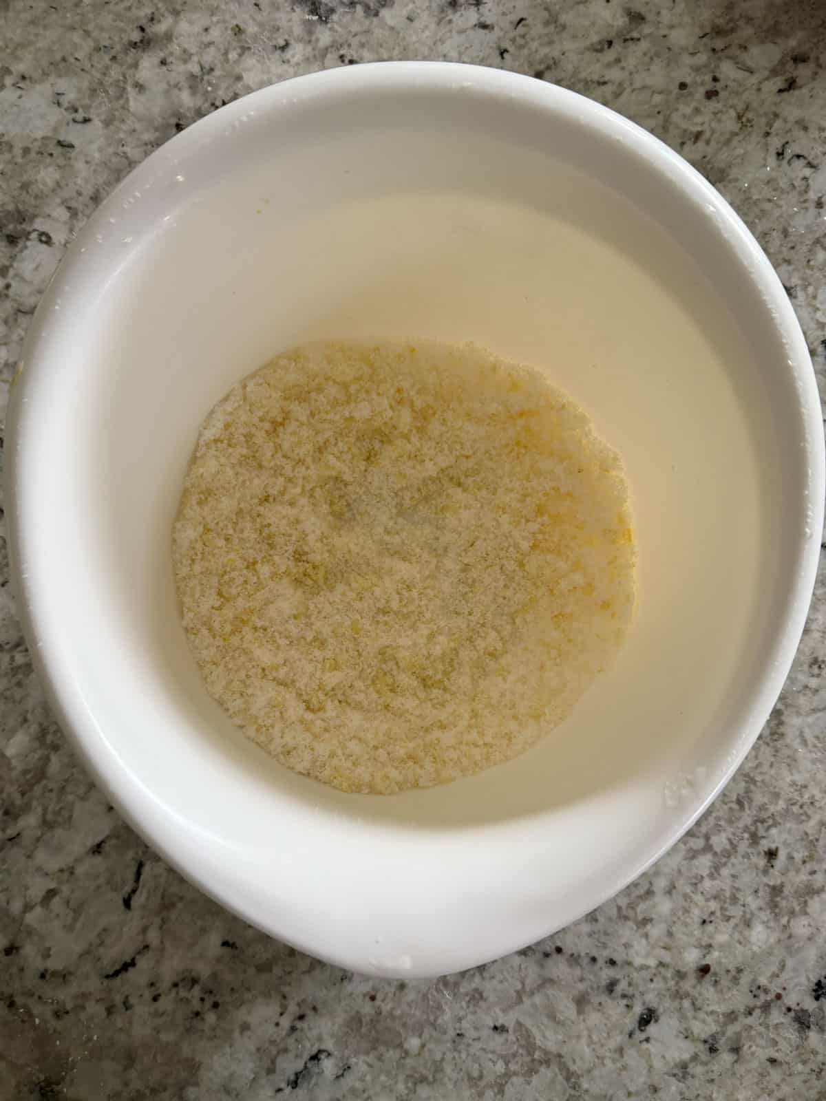 Lemon zest and granulated sugar being mixed together in a bowl.