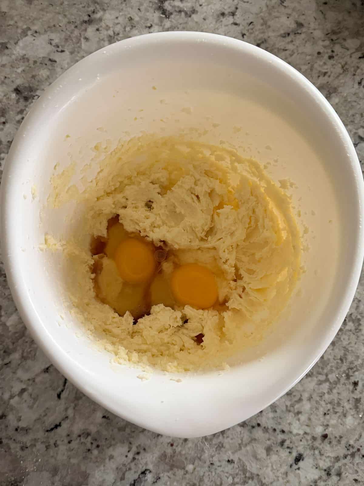 Eggs and vanilla extract being added to the butter sugar mixture in a bowl.