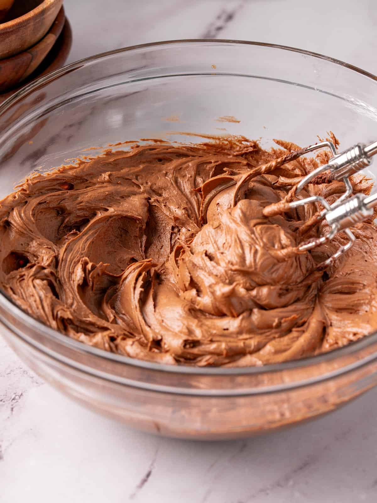 Sour cream icing in a glass bowl with beaters showing the texture.