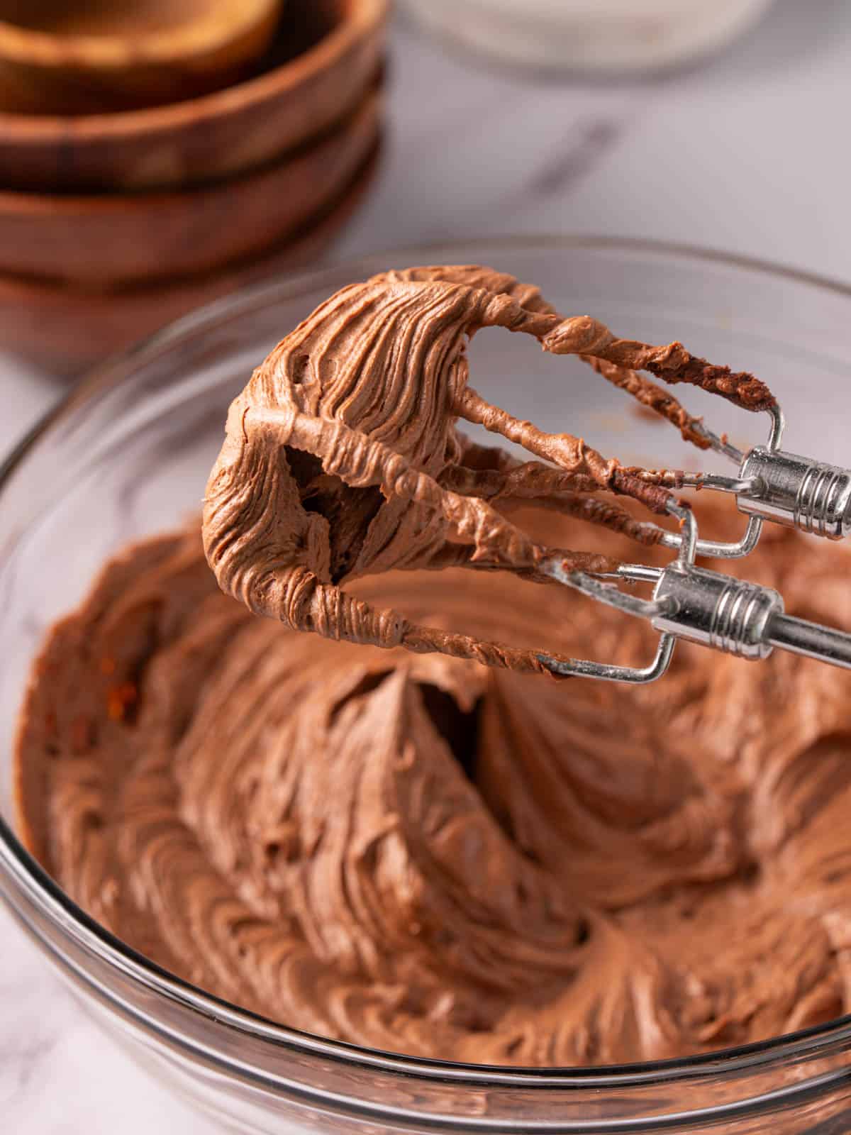 Frosting on beaters coming out of a glass bowl on the counter.