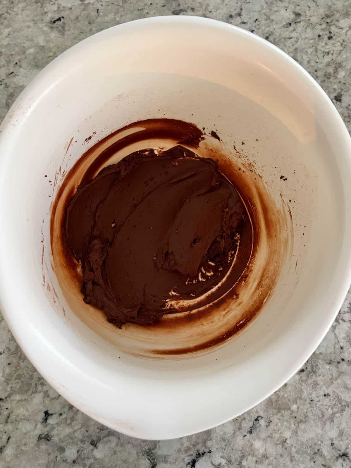 Butter and unsweetened cocoa powder mixed together in a white bowl.