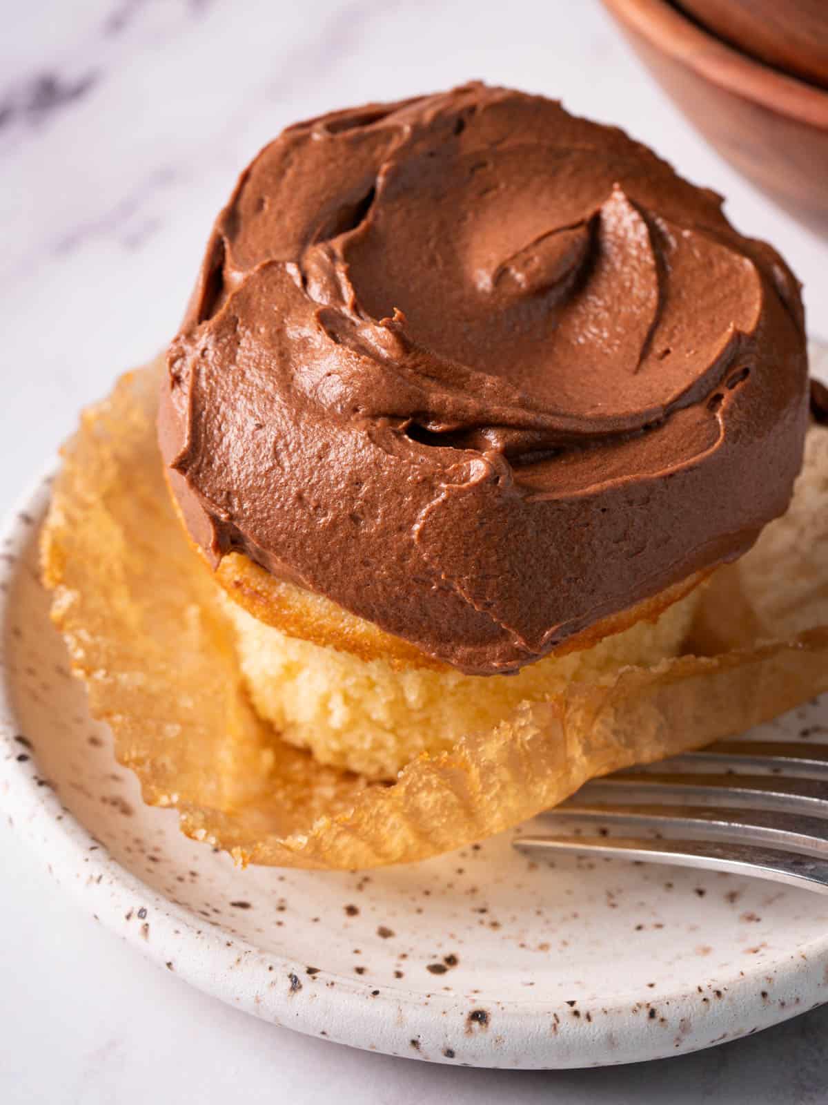 A swirl of sour cream frosting on a cupcake on a plate.