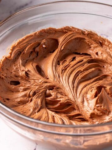 Chocolate sour cream frosting in a glass bowl on the counter.