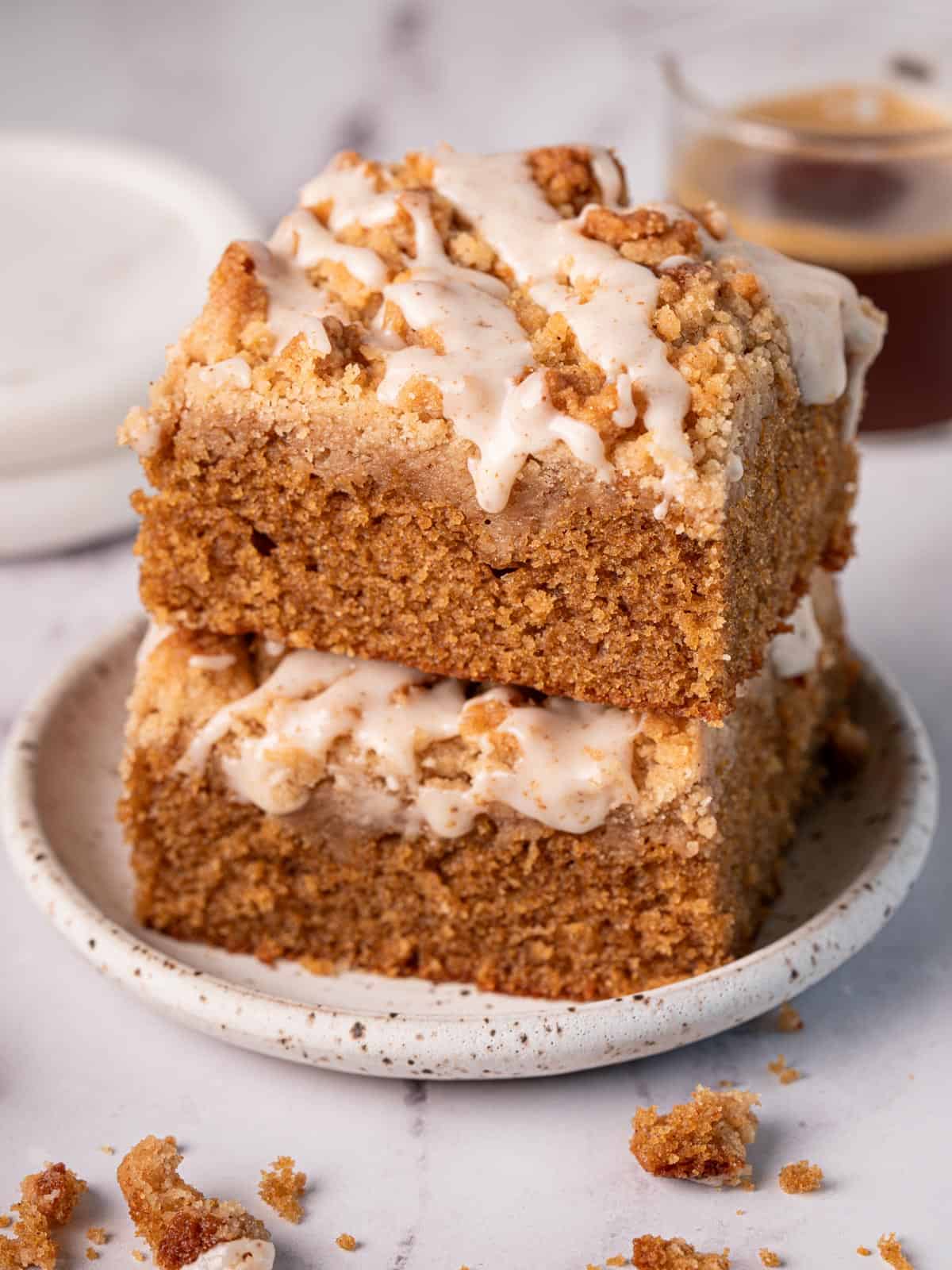 Stack of coffee coffee cake on top of each other on a plate with icing on top.