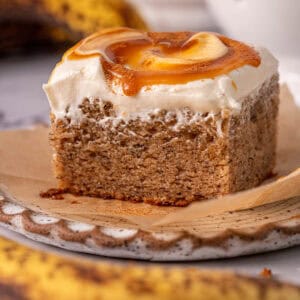 A slice of the best spiced banana cake on a plate with cream cheese frosting.