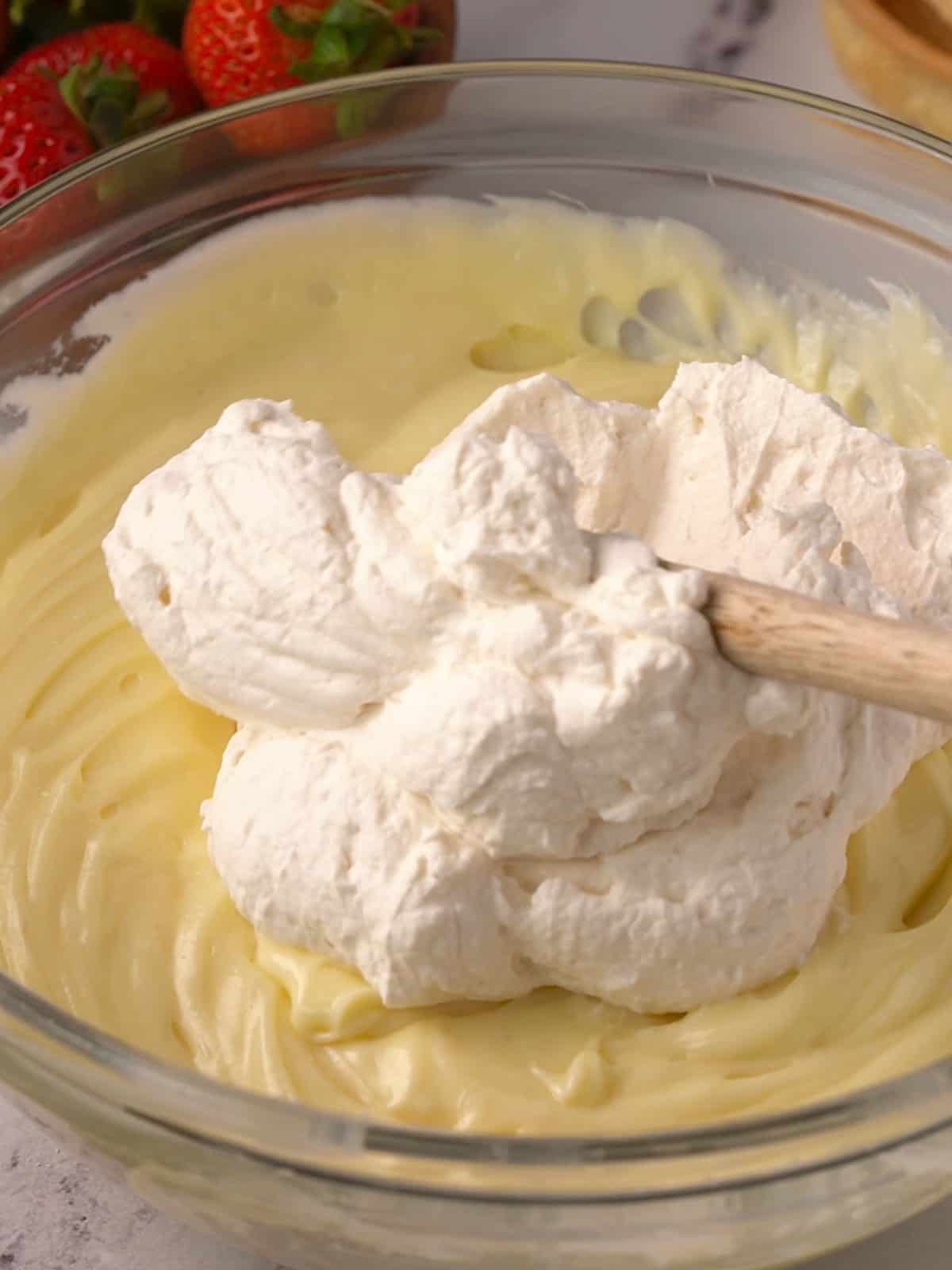 Adding the whipped cream into the white chocolate ganache in a bowl.