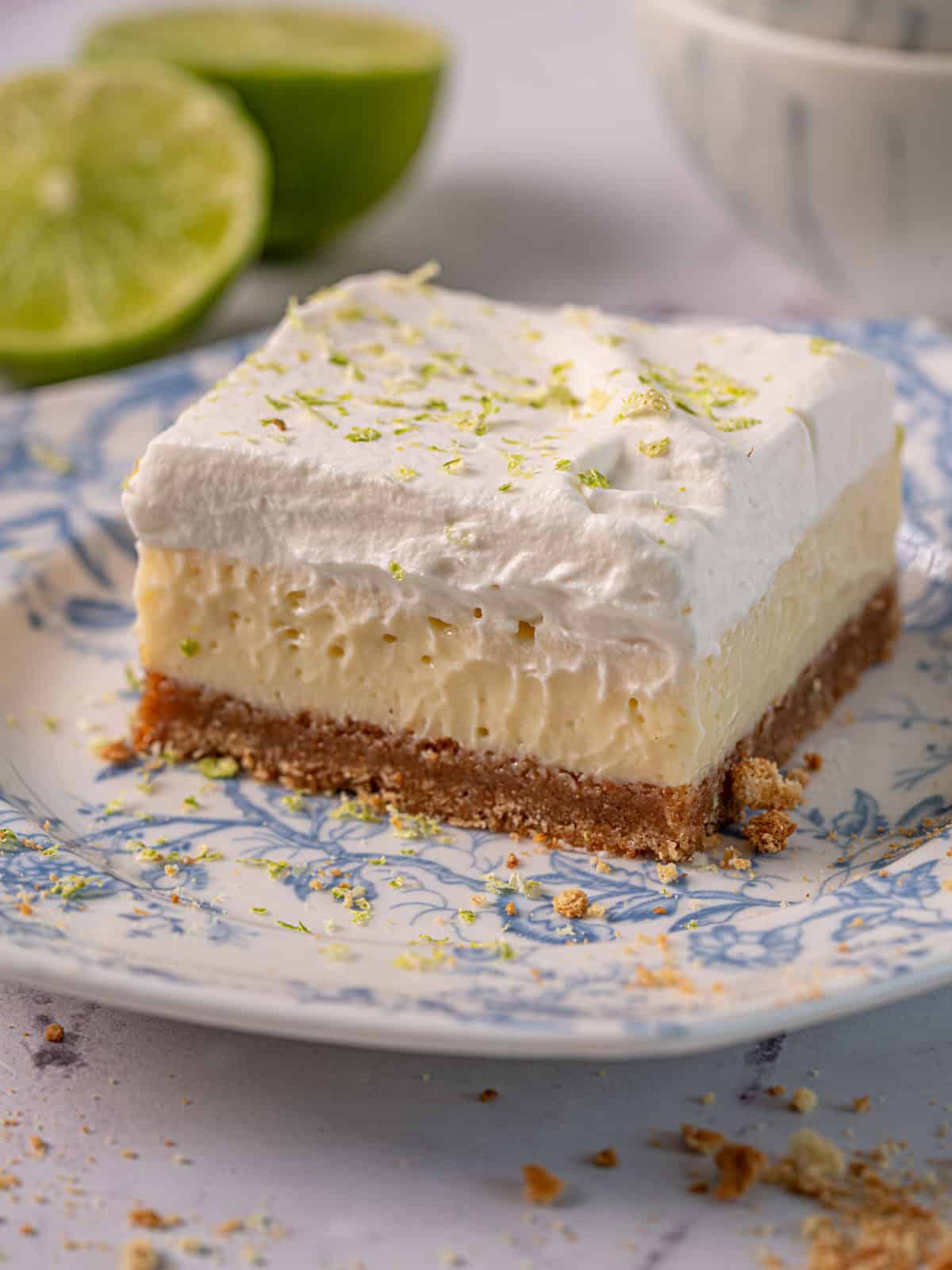 Lime ginger cheesecake on a plate with whipped cream and lime zest.
