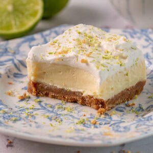 Lime and ginger cheesecake on a plate showing the creamy texture and ginger crust.