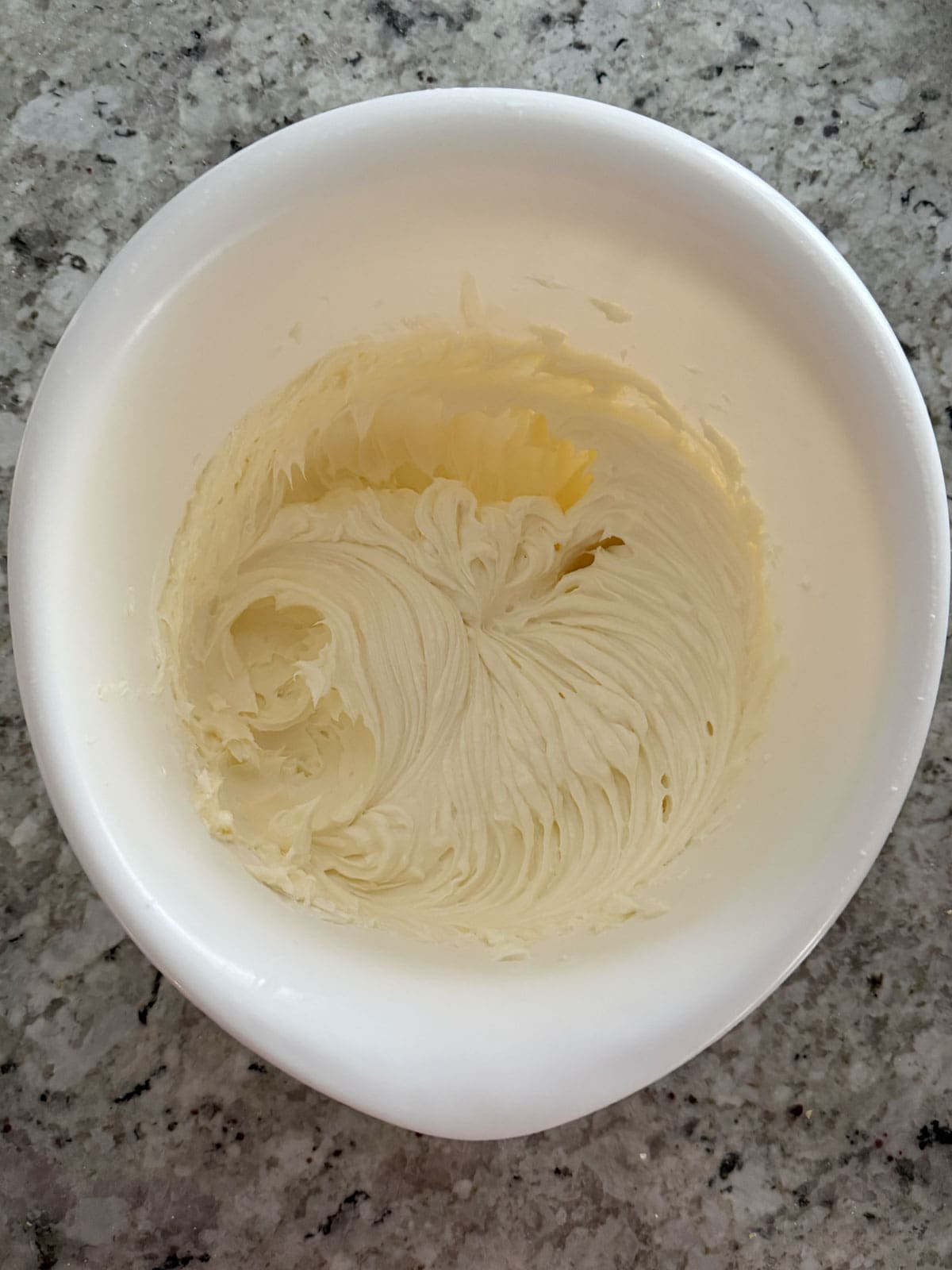 Mascarpone, cream cheese, and granulated sugar being mixed until smooth in a bowl.