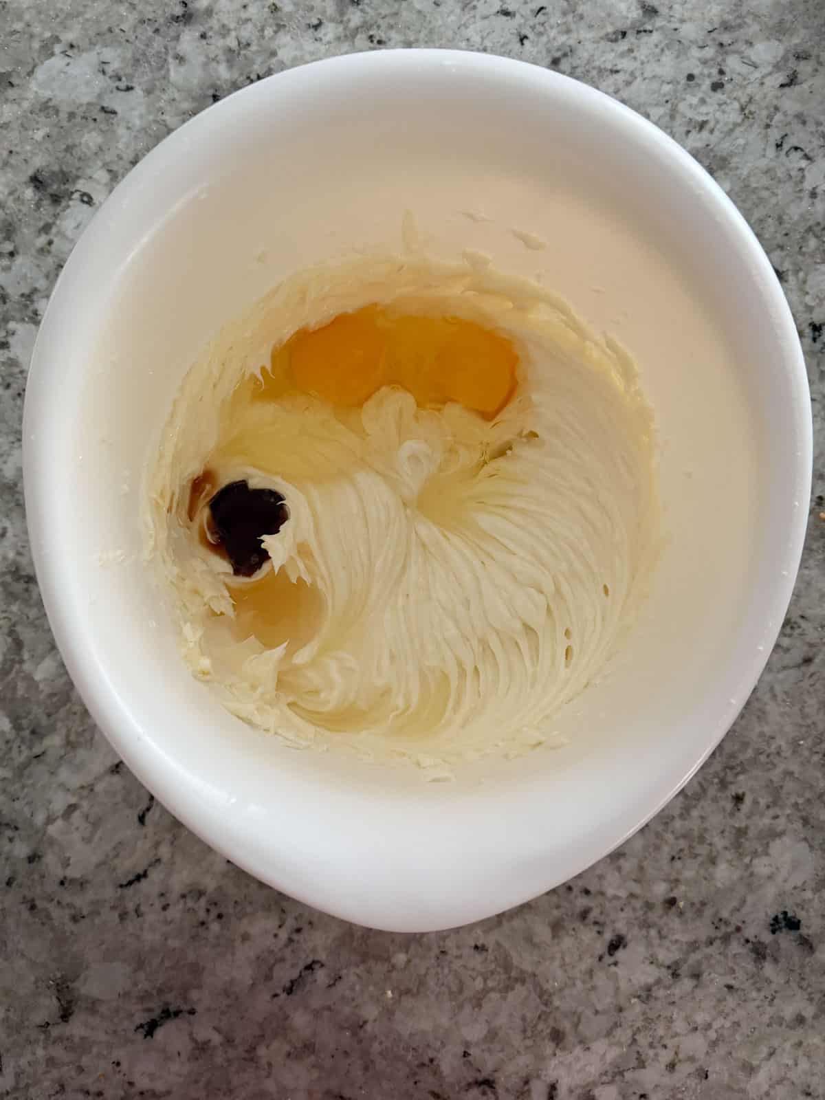 Adding the eggs, vanilla extract, and lemon juice to the cheese mixture in a bowl.