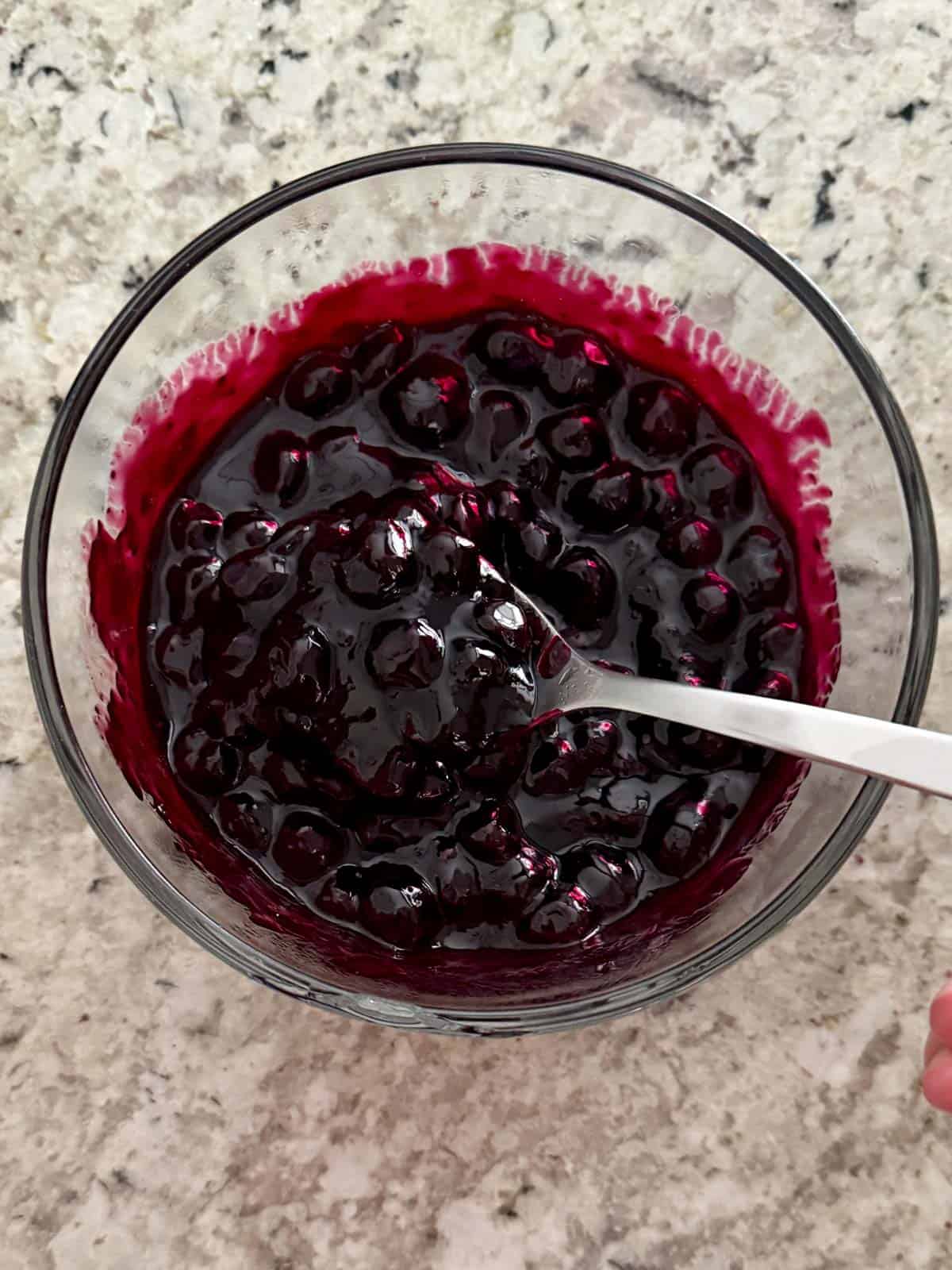 Blueberry compote in a bowl with a spoon in it showing the texture.