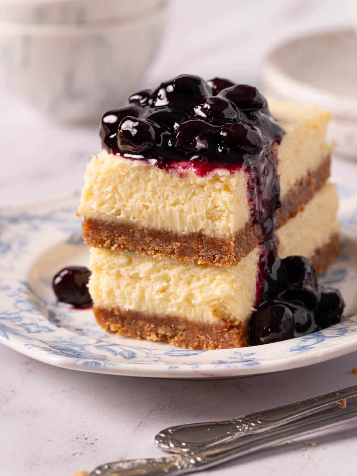 Simple mascarpone cheesecake bars with compote on top with forks around it.