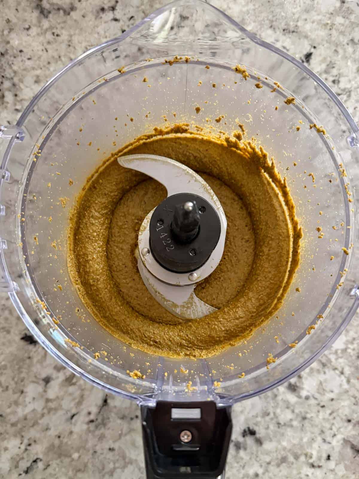 Pistachios being ground up in a food processor to create a paste.