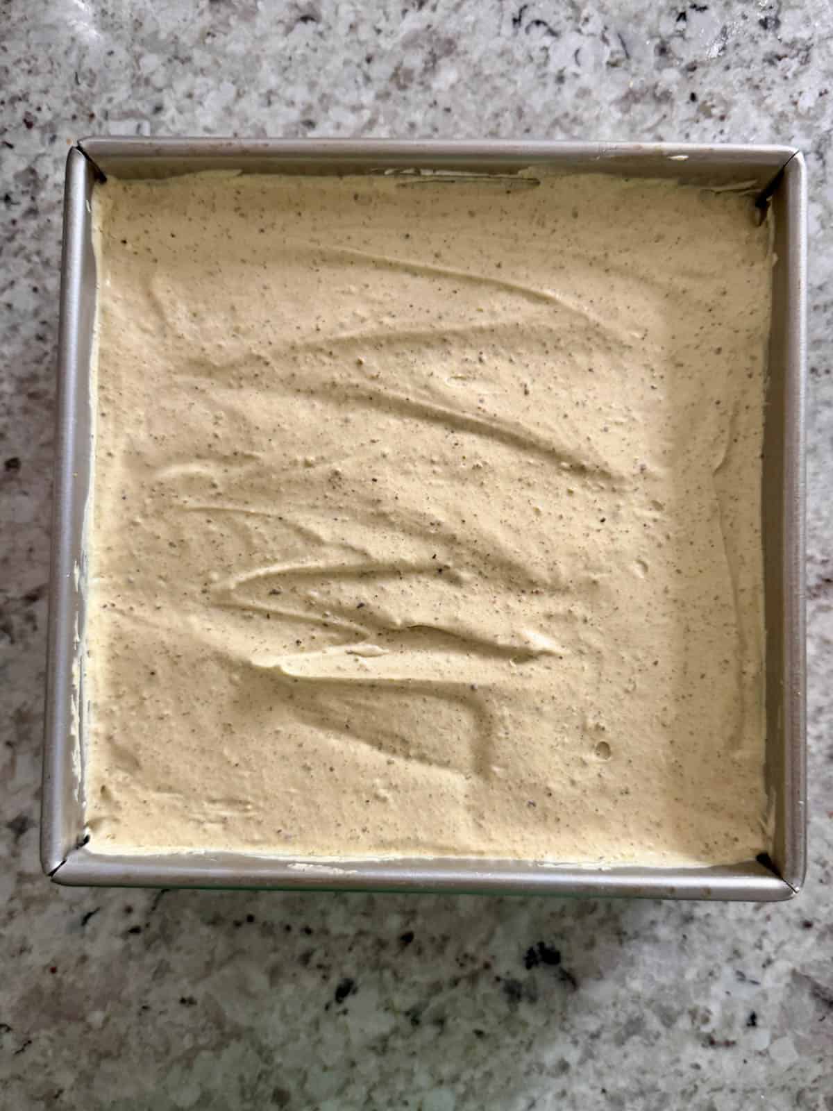 The pistachios ice cream in a metal pan ready to be frozen.