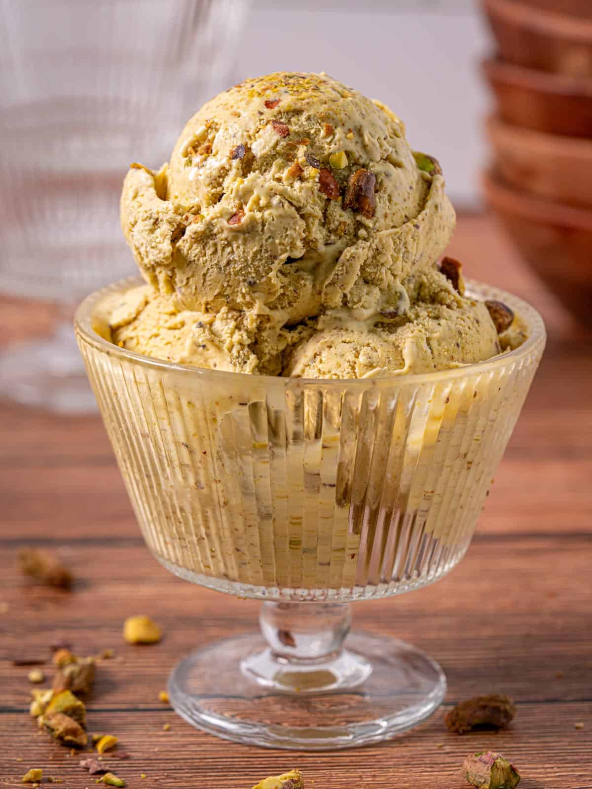 Ice cream pistachio in a glass dish with pistachios around it and on top.