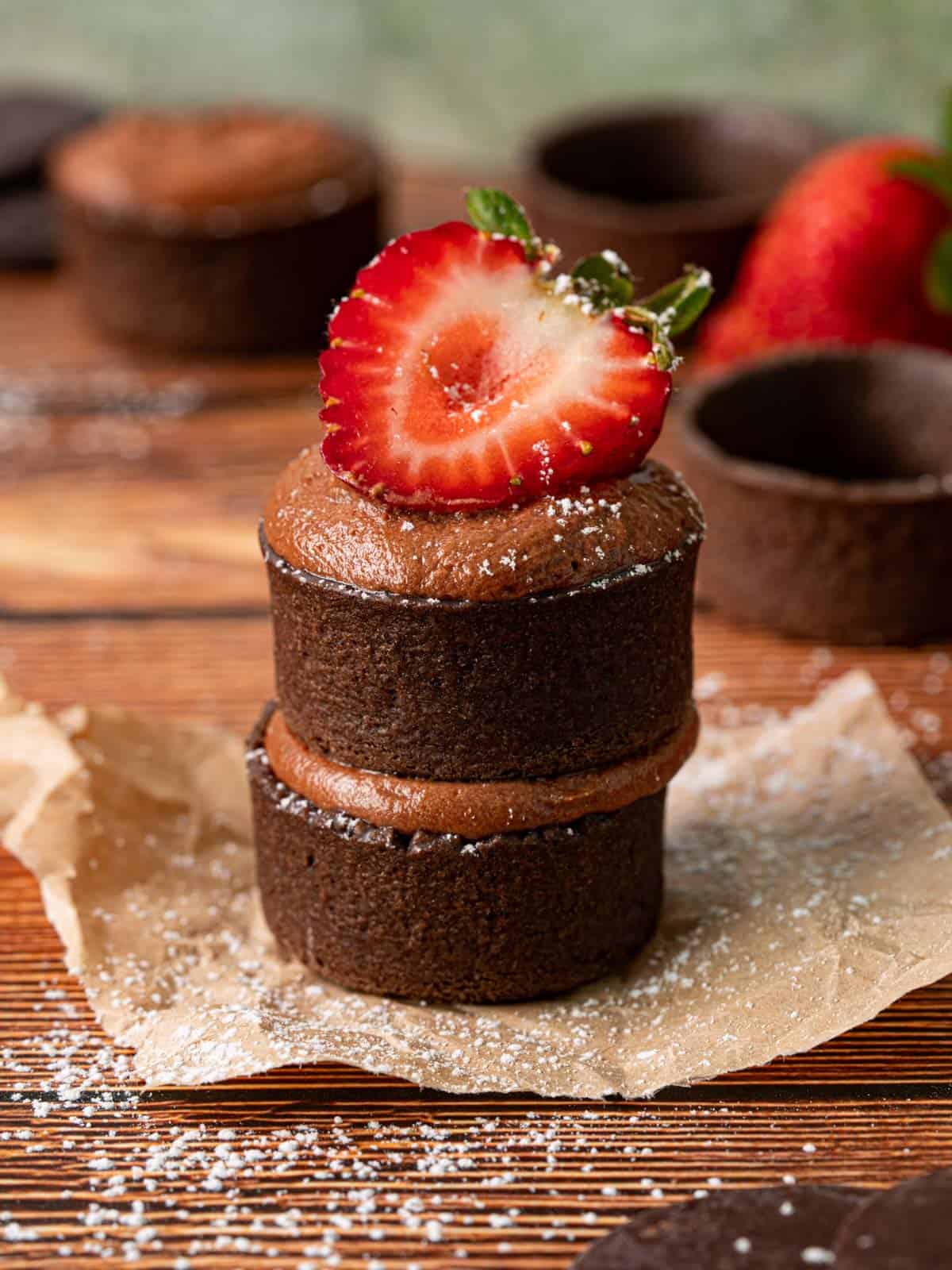 No bake strawberry chocolate tartlets stacked on top of each other with fresh strawberries.