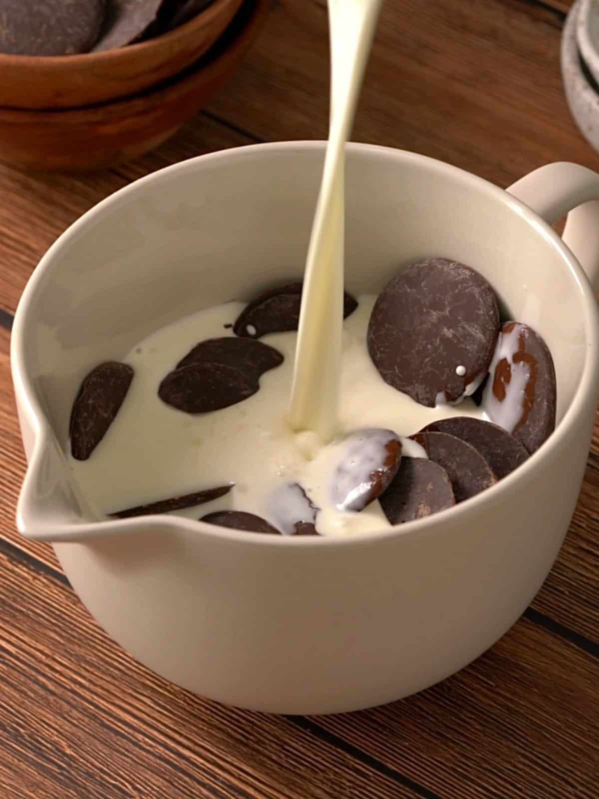 Pouring the hot heavy cream over the chocolate in a bowl to make the ganache.