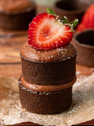 Chocolate strawberry tartlets stacked on top of each other with fresh strawberries.