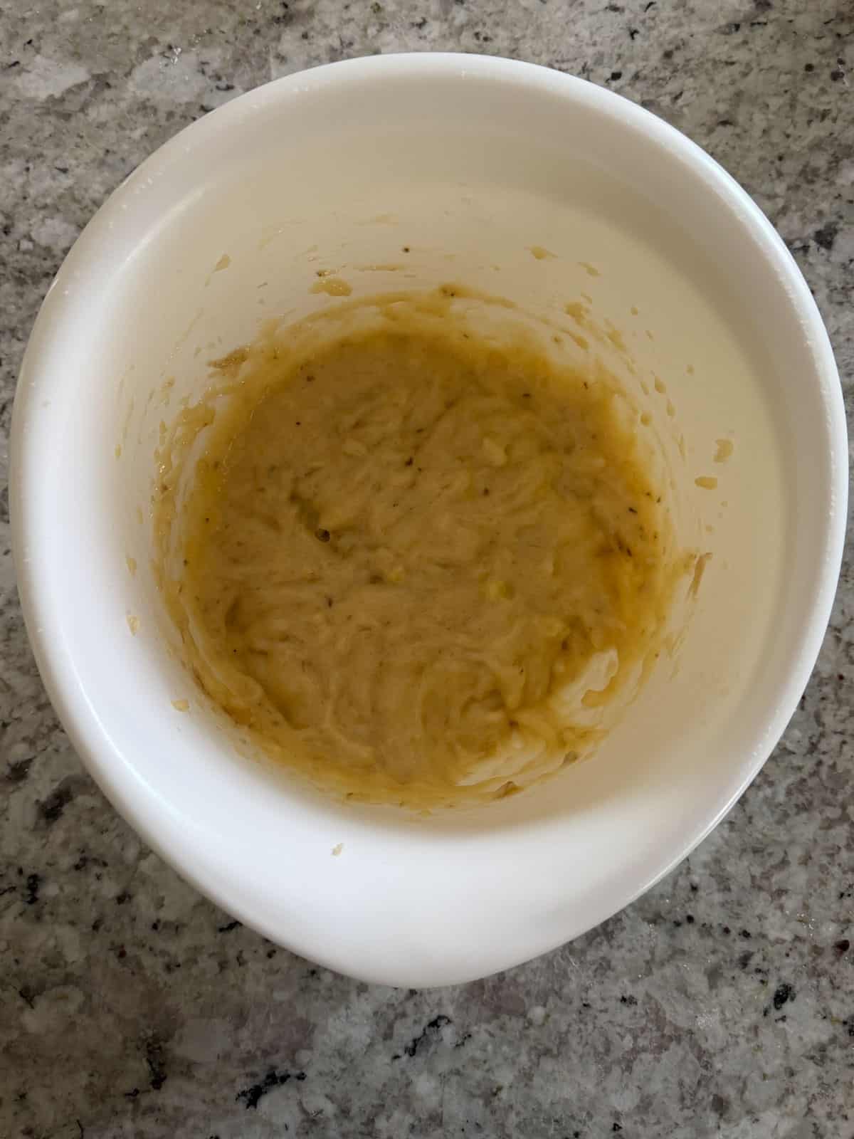 Mashed bananas in a bowl with a spatula mixed until smooth.