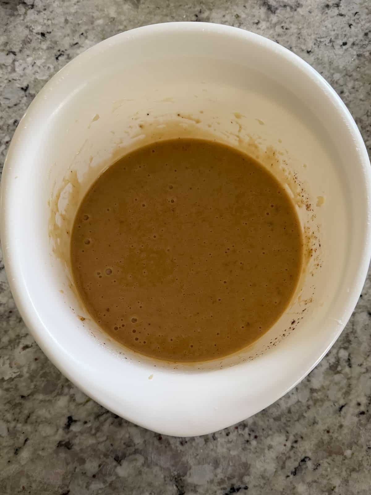 Adding instant coffee granules to the banana sugar and butter mixture in a bowl.