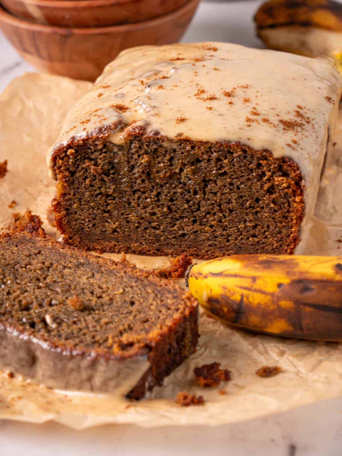 Banana bread coffee loaf on a piece of parchment with coffee glaze on top.
