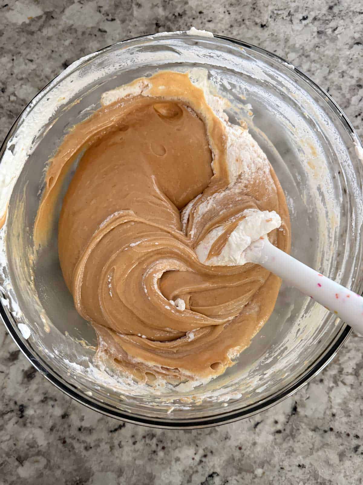 Adding the heavy cream mixture to the peanut butter mixture in a bowl.