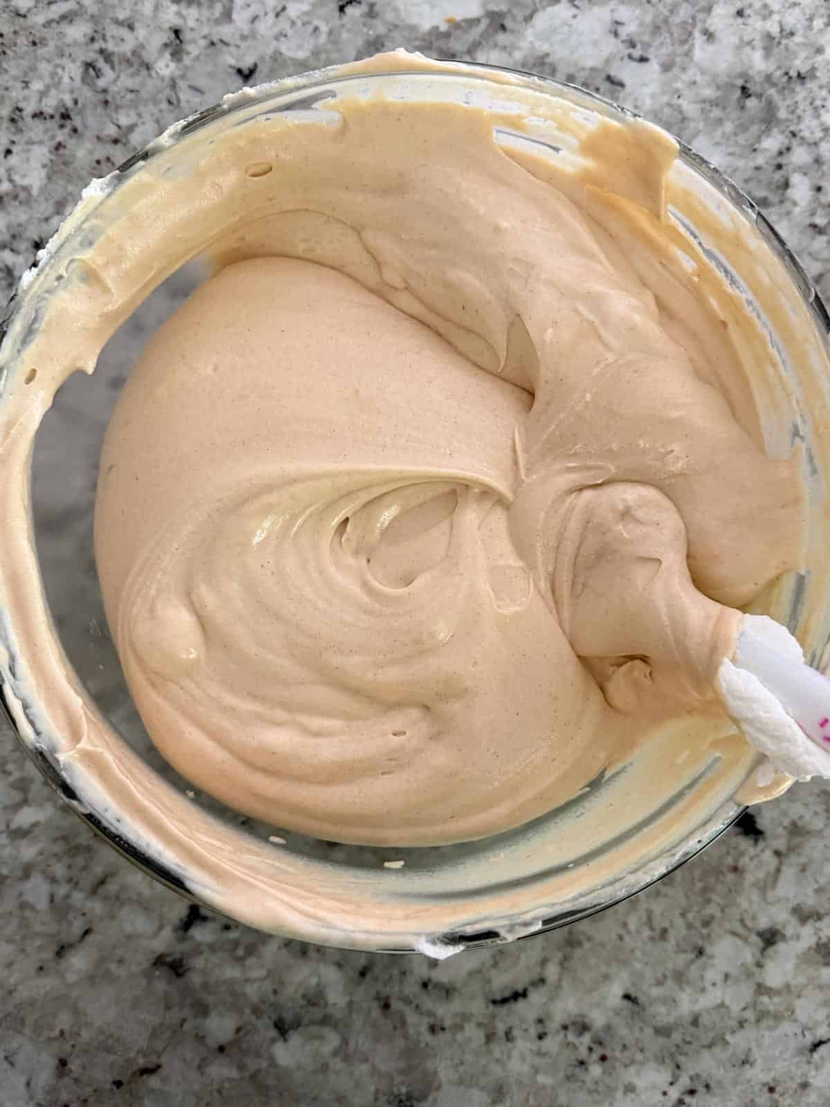 Folding and swirling in the whipped heavy cream into the peanut butter mixture in a bowl.