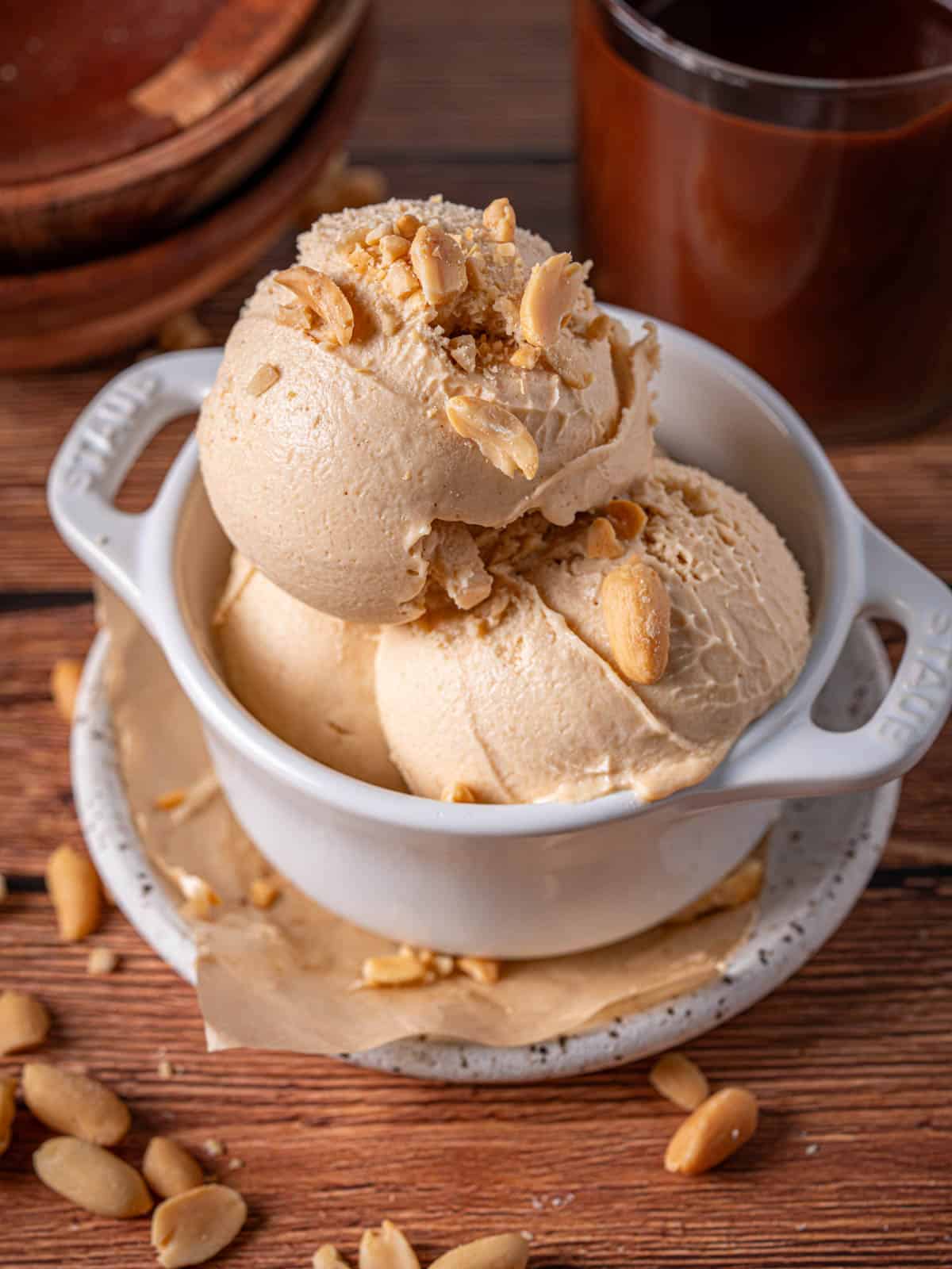 Scoops of ice cream in a bowl with chopped peanuts on top.