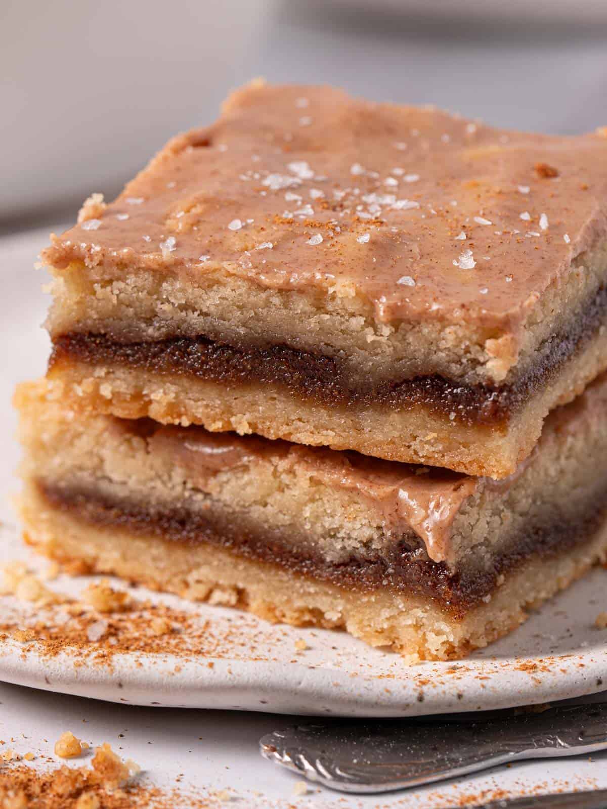 Stacked bars with cinnamon icing and shortbread crumbs around the plate.