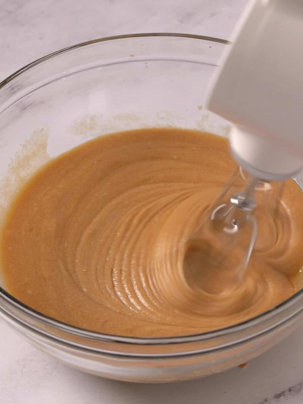 Melted butter, eggs, vanilla, and sugars being mixed together until combined.