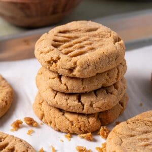 A stack of soft peanut butter cookies on a baking sheet.