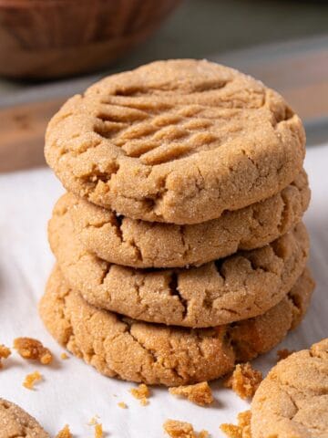 A stack of soft peanut butter cookies on a baking sheet.