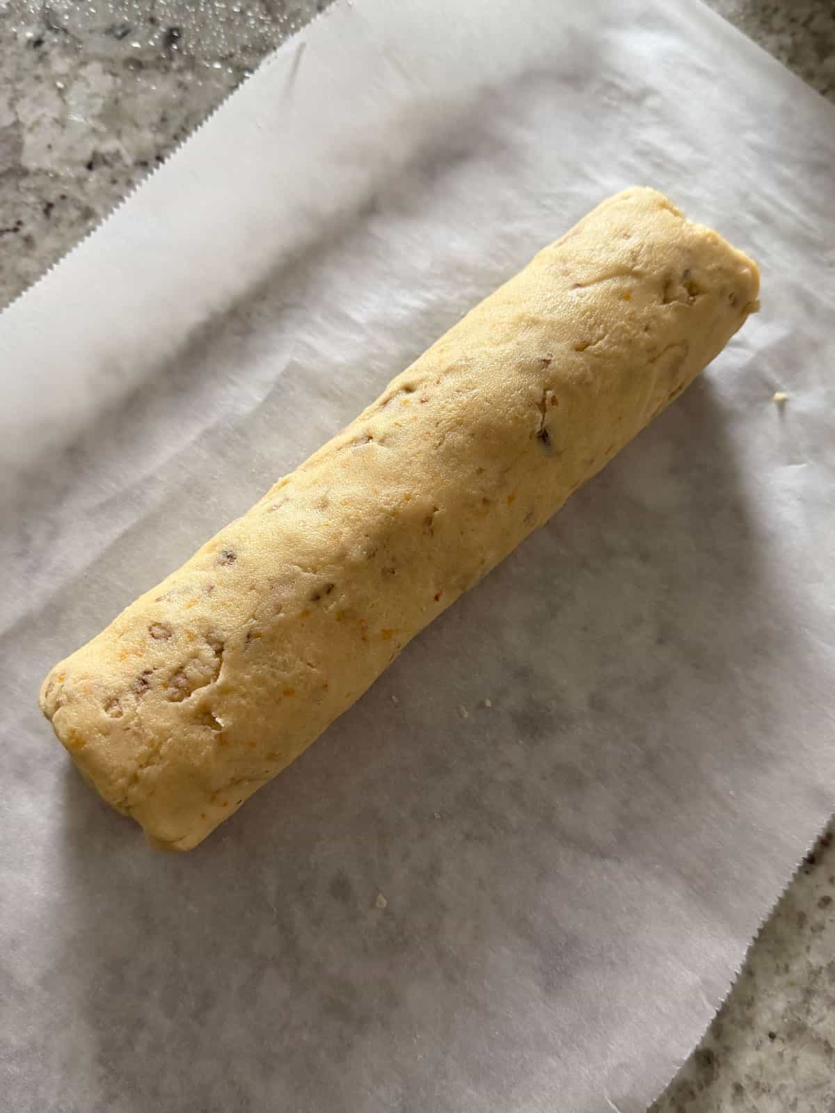 The shortbread dough rolled into a log before slicing on parchment paper.