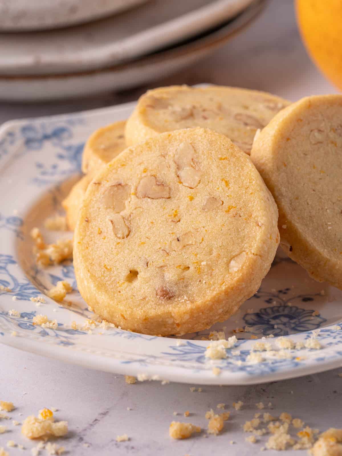 Slice and bake shortbread cookies with walnuts on a plate with crumbs.