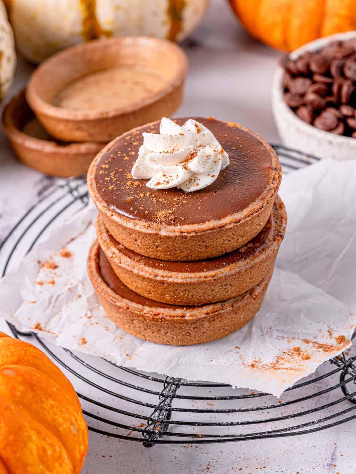 Pumpkin tarts stacked on top of each other with whipped cream on top.