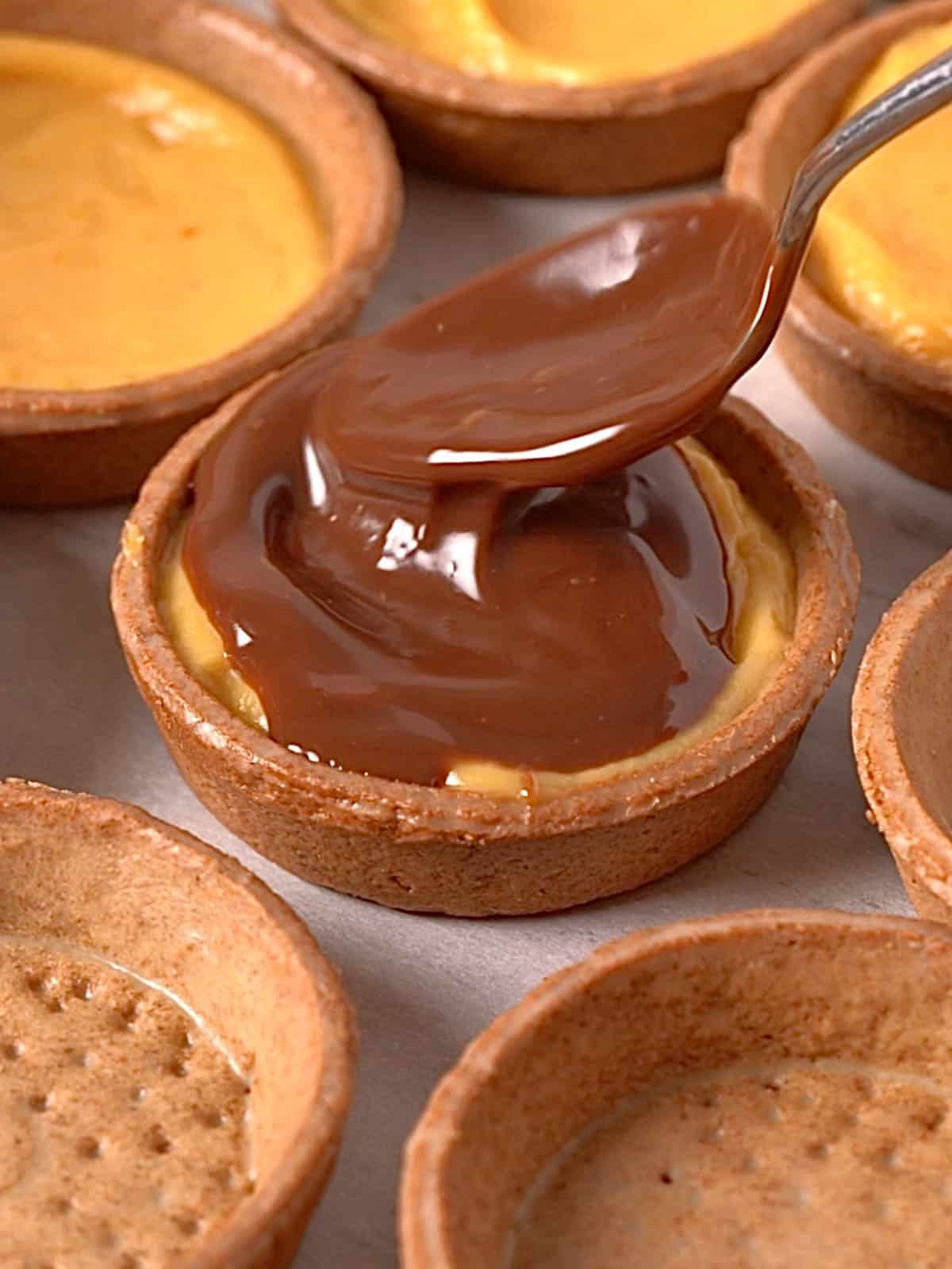 Filling the graham cracker tart shells with the cream and chocolate ganache.