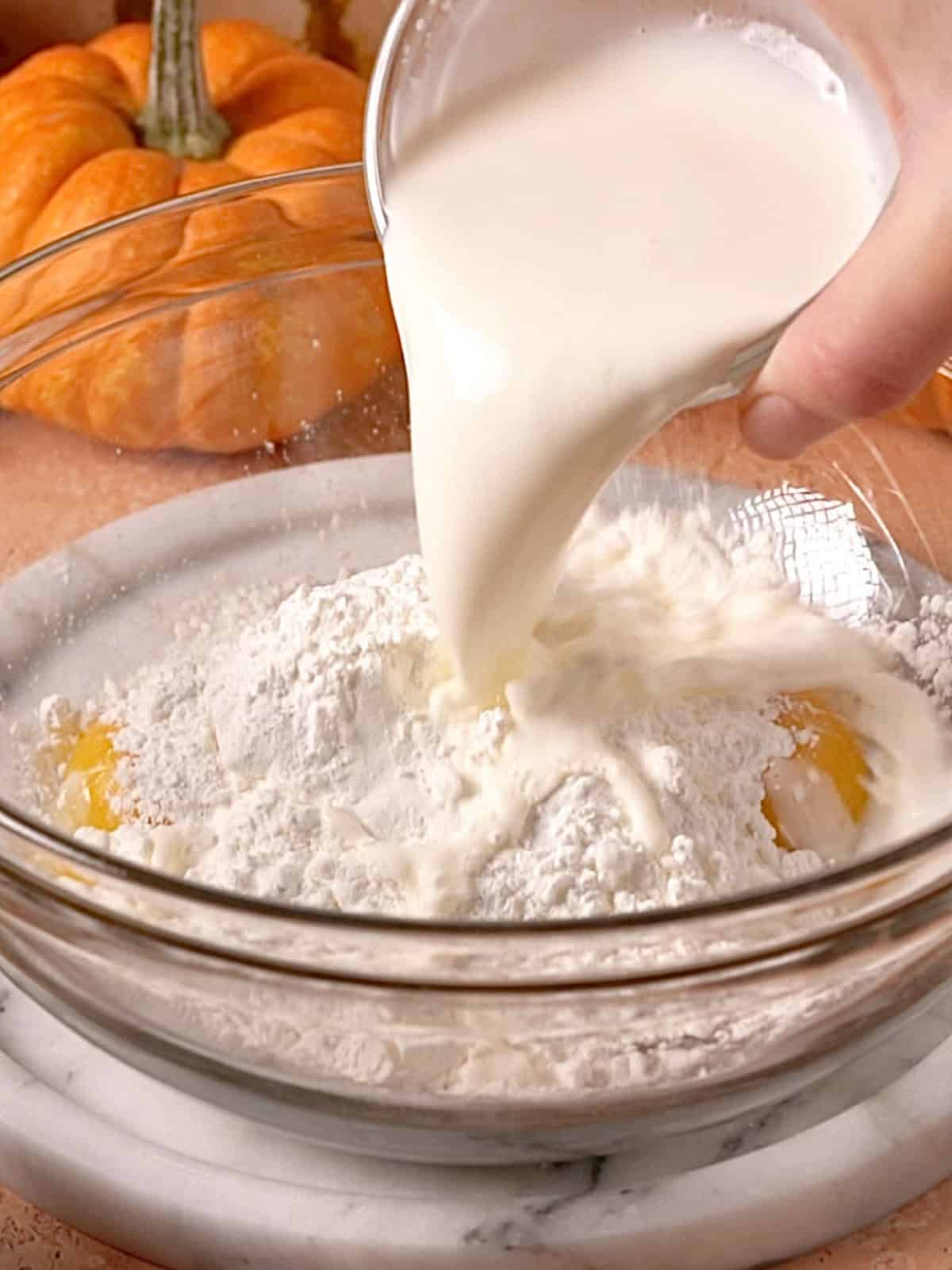 Egg yolks, sugar, milk, and cornstarch in a bowl being mixed together.