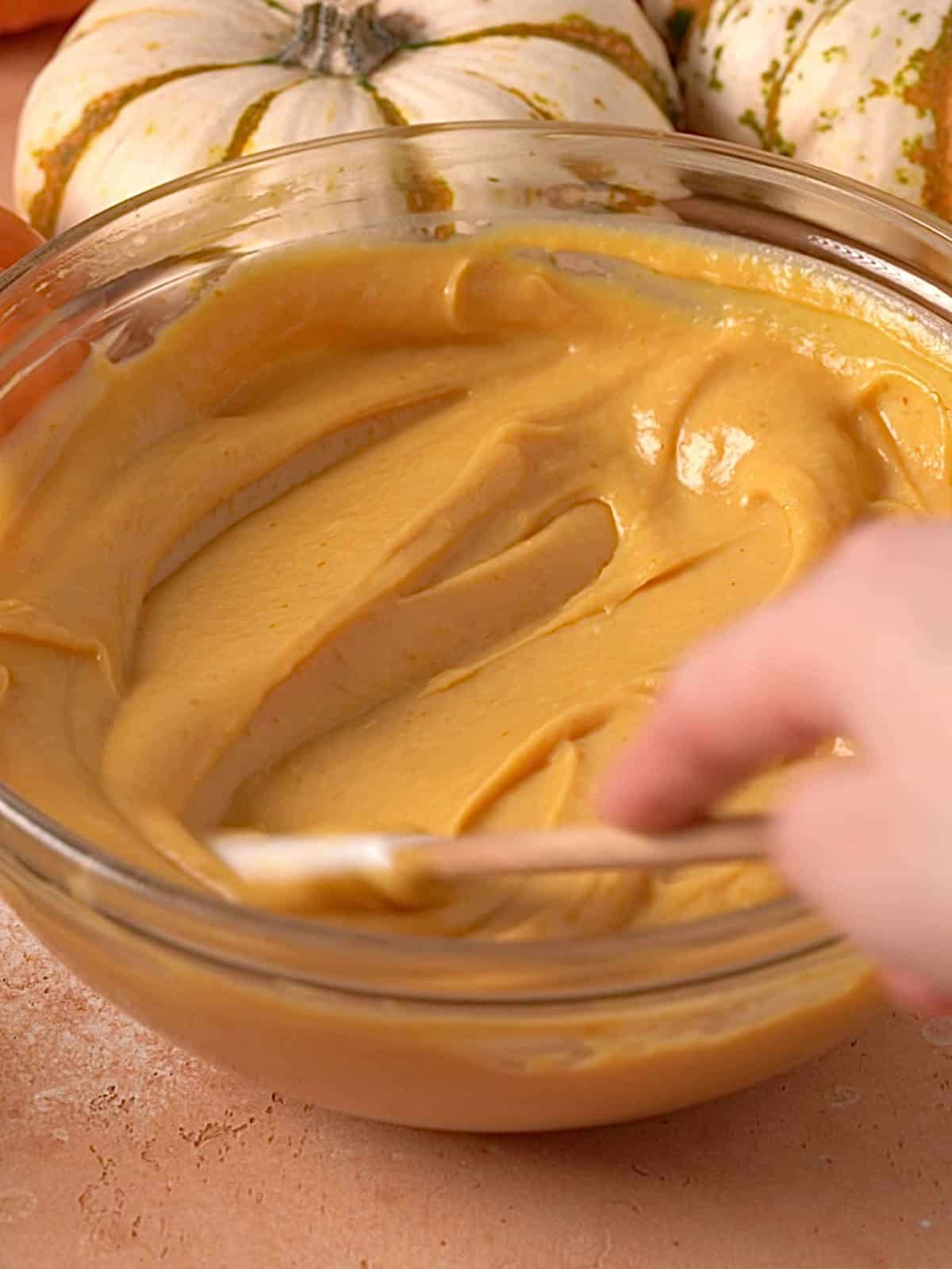 Pumpkin pastry cream in a bowl being stirred together.