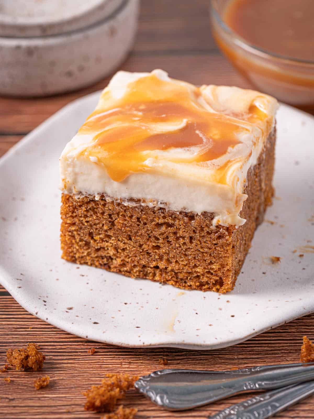 A slice of pumpkin cake with caramel on top with crumbs around it.